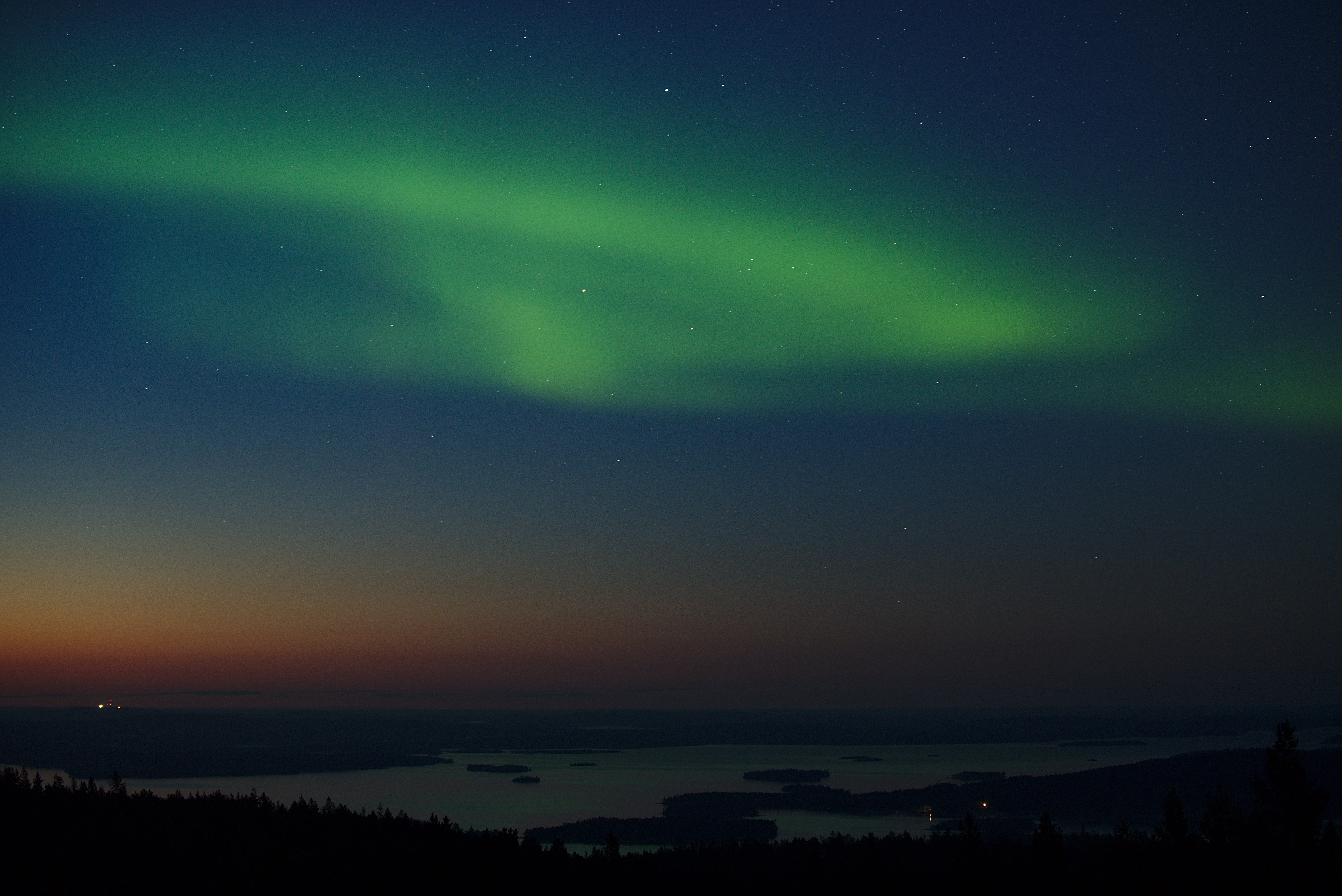 Northern lights over lake inari with sunset colours in the sky